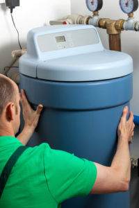Blue water conditioning unit being installed by a technician.