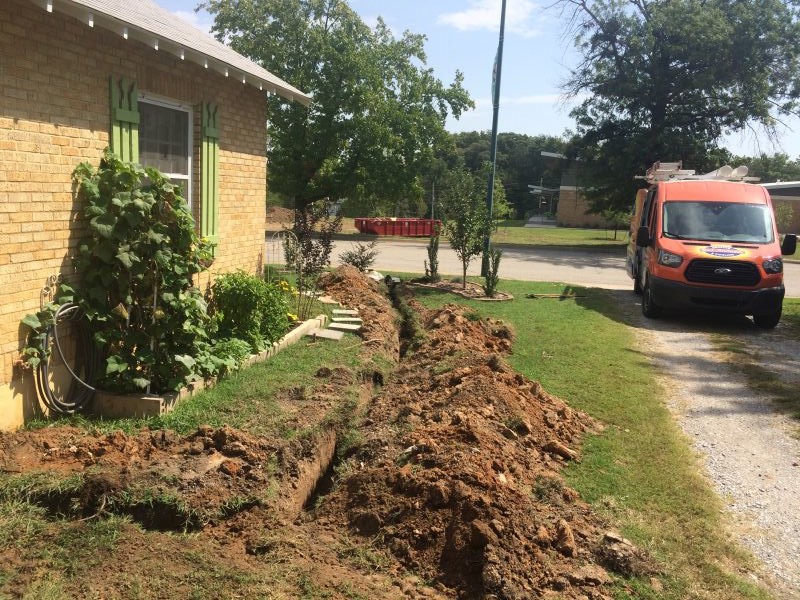 Sewer line dug out by the side of a house.