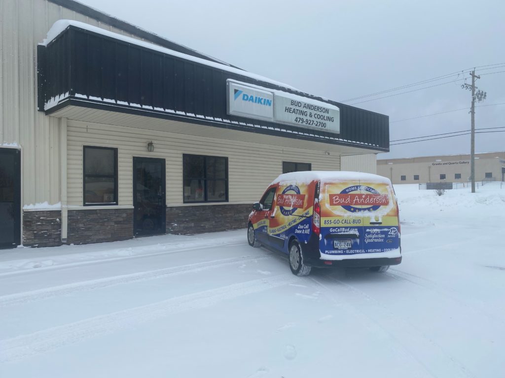 Bud Anderson Heating & Cooling fleet vehicle parked in snowy parking lot outside of storefront.